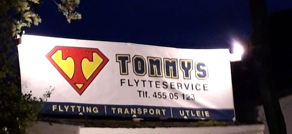 Det opplyste firmaskiltet til Tommys Flytteservice utenfor basen.